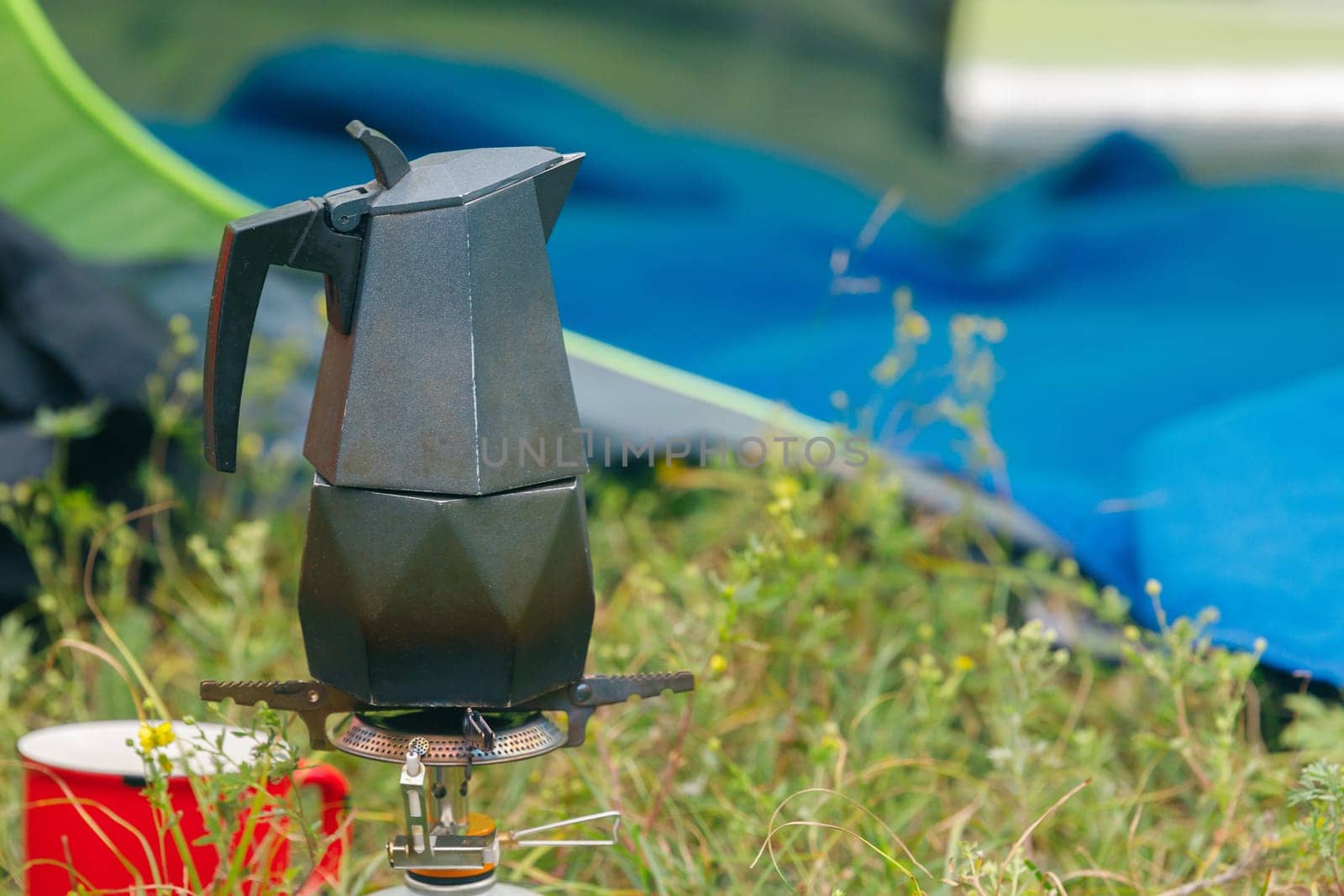 Brewing a rich cup of coffee outdoors using a moka pot on a camping stove in a tranquil, serene setting