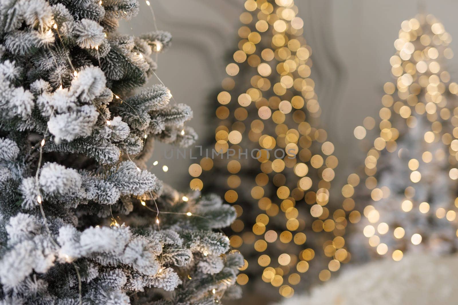 snowy fir tree close-up with garland and blurred lights in the background. New Year and Christmas celebration concept