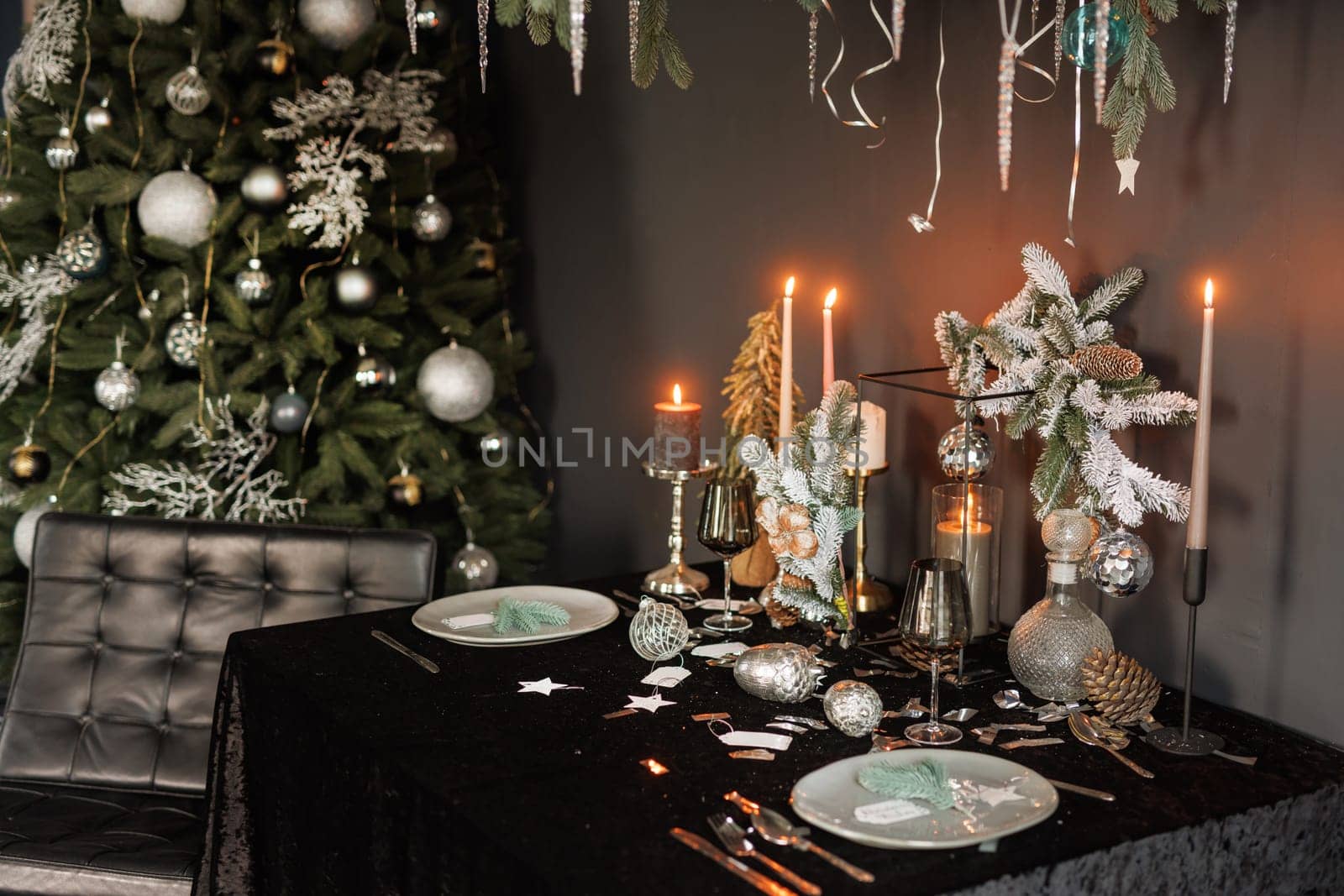 Christmas and New Year decorated with dark interior of the room. Festive Christmas night with candles on the table and beautiful dishes
