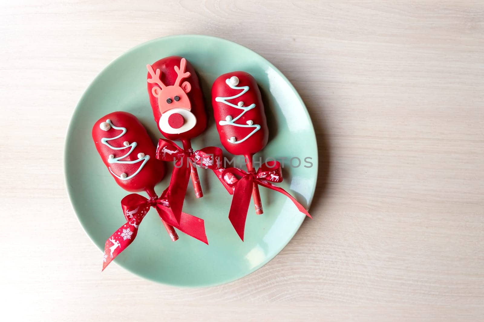 Flat lay of cake pops ice cream on a stick in pink glaze with strawberries and blueberries on a light background.