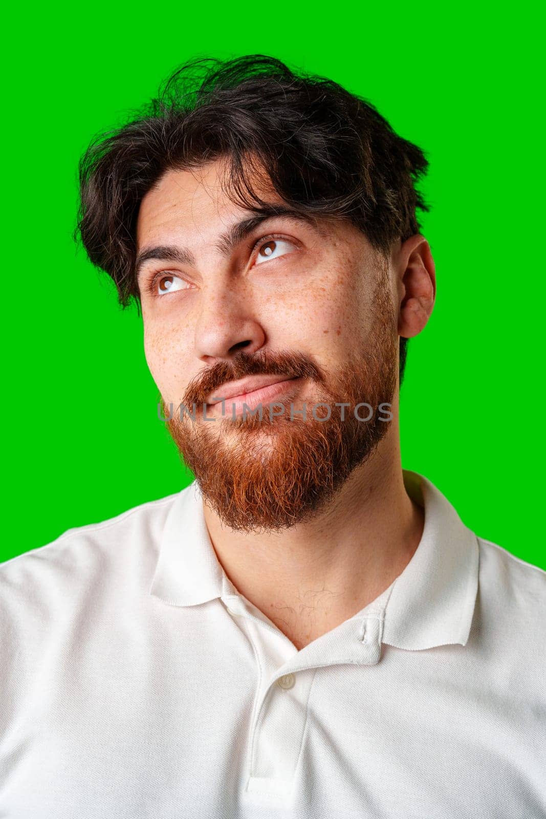 A man with a beard smiles confidently against a bright green background close up