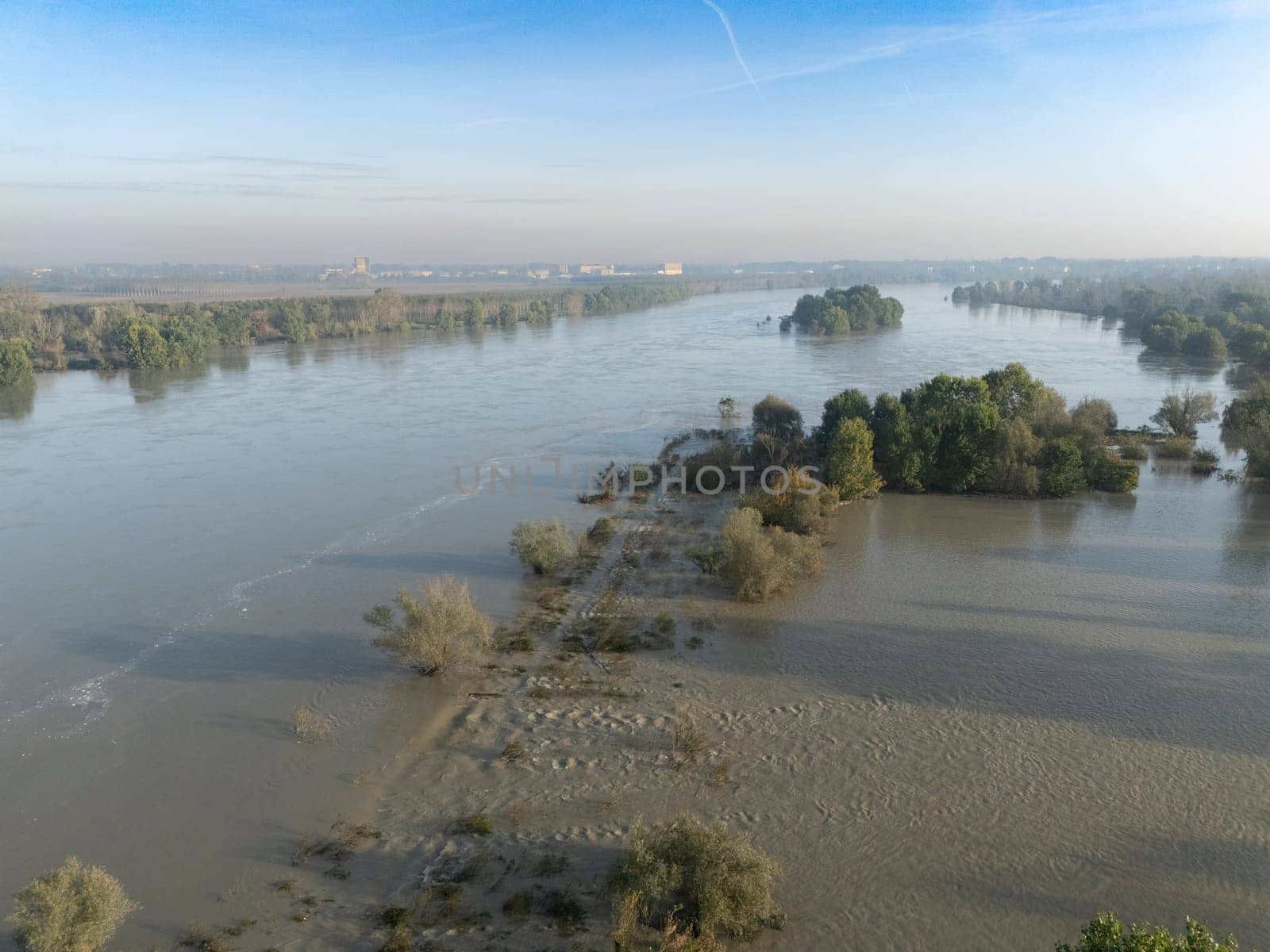 Stagno Lombardo, Italy - October 20th 2024 Aerial view of a river flooding the surrounding fields and forests after a heavy rain period, with the cloudy sky in the background
