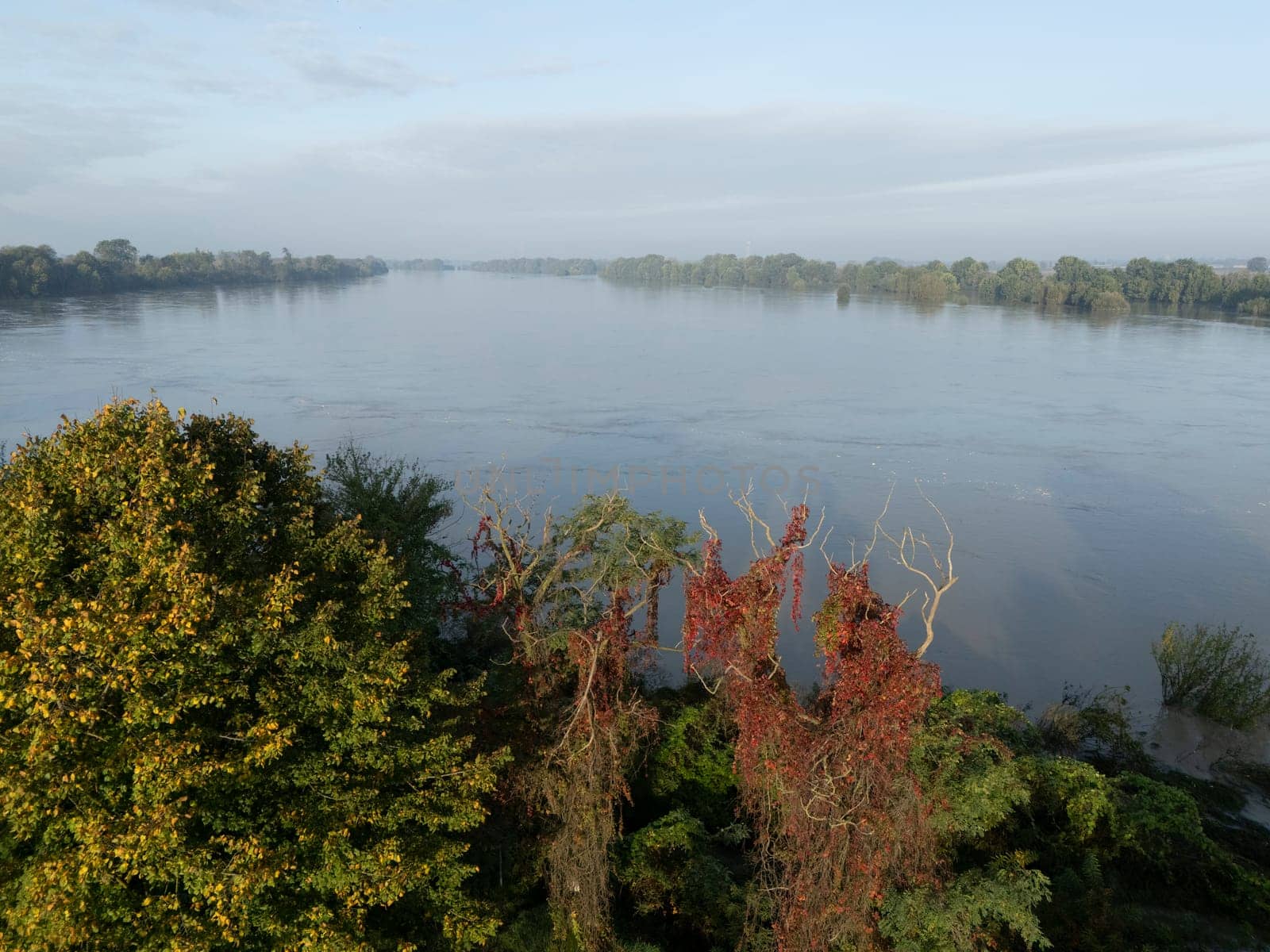 Stagno Lombardo, Italy - October 20th 2024 Aerial view of a river flooding the surrounding fields and forests after a heavy rain period, with the cloudy sky in the background