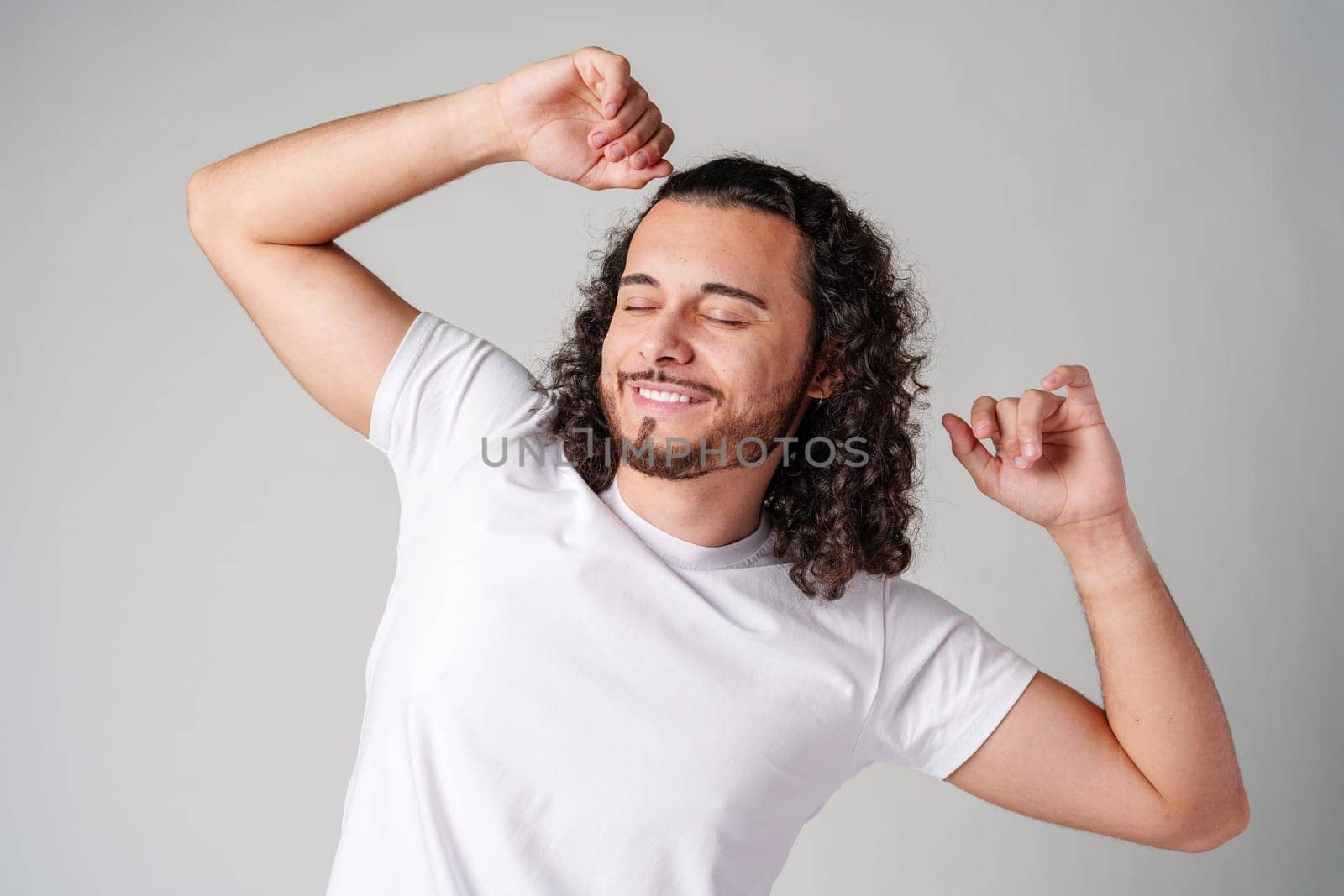 Happy man celebrating success with raised fists in a studio against a plain background close up