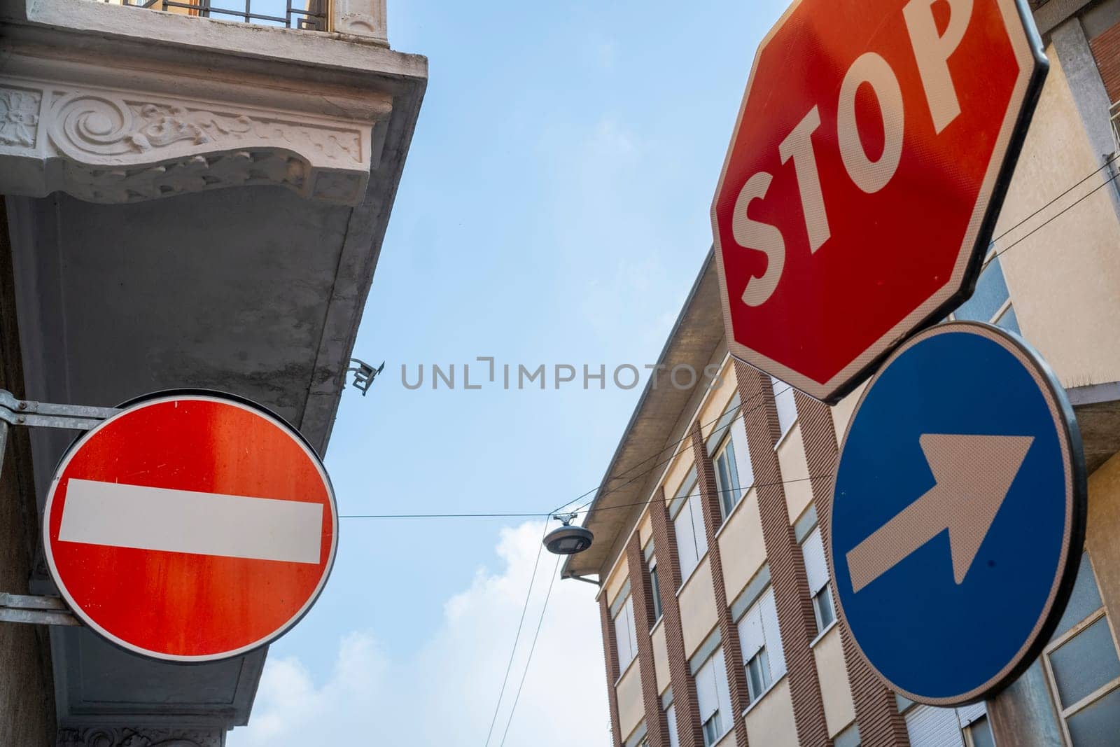 Cremona, Lombardy, Italy October 15th 2024 One way and stop signs are pointing different directions against a blue sky with some clouds