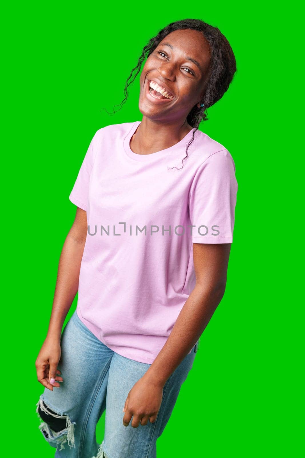 A joyful young woman smiling brightly while standing against a vivid green background in studio
