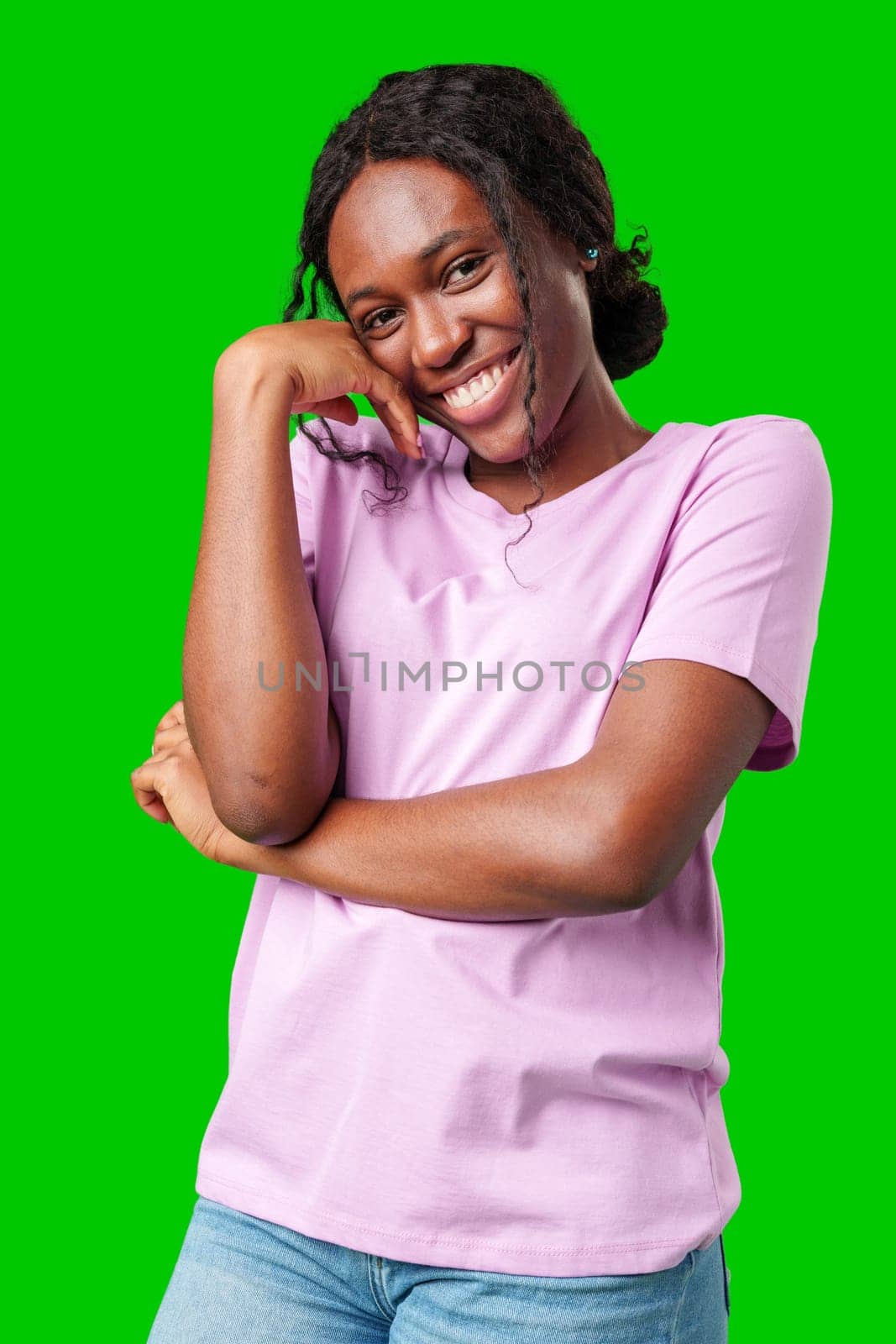 Happy young person laughing and playfully covering face while standing against a bright green background in studio