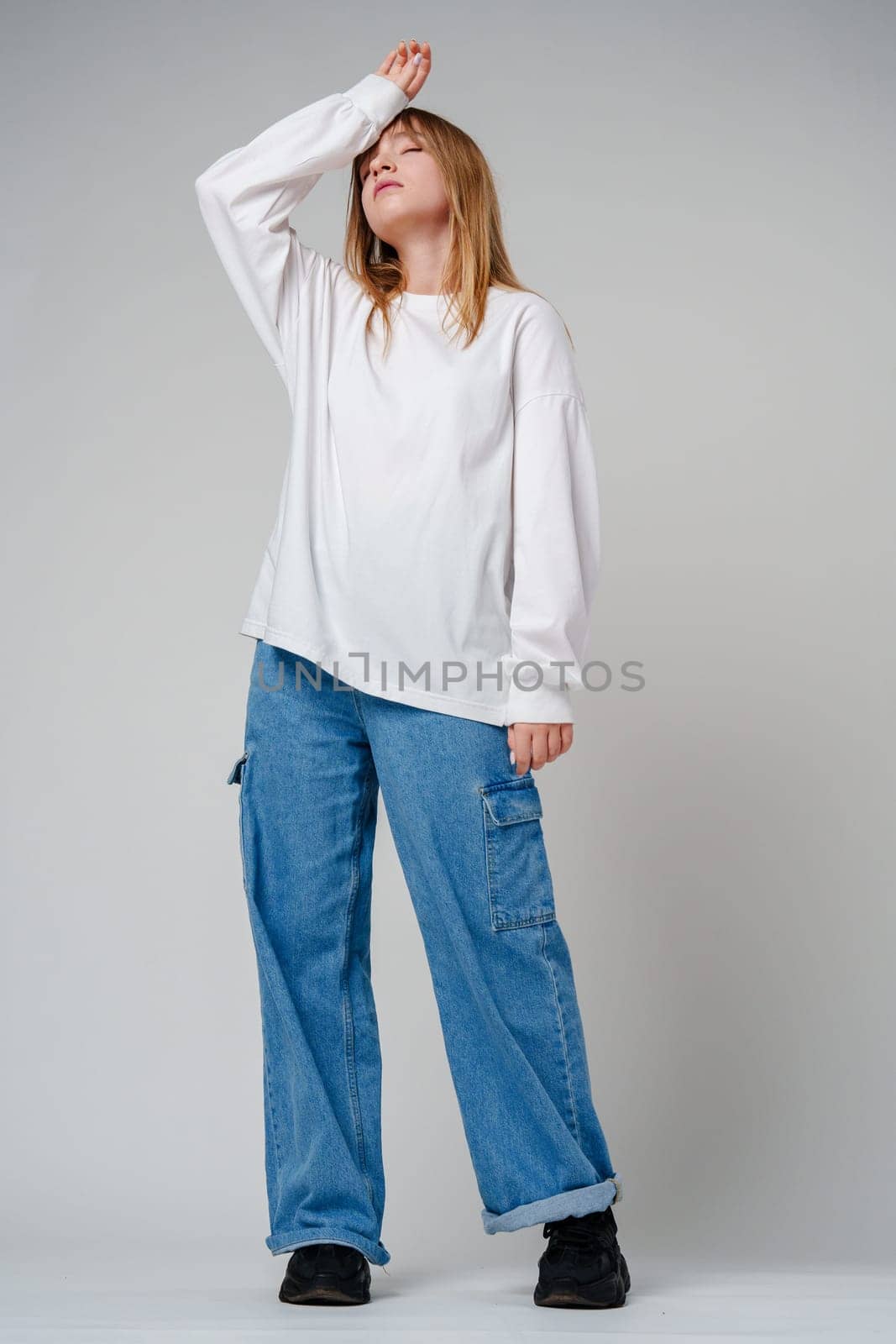 A young woman in a white long-sleeve shirt expressing a moment of contemplation against a neutral background close up