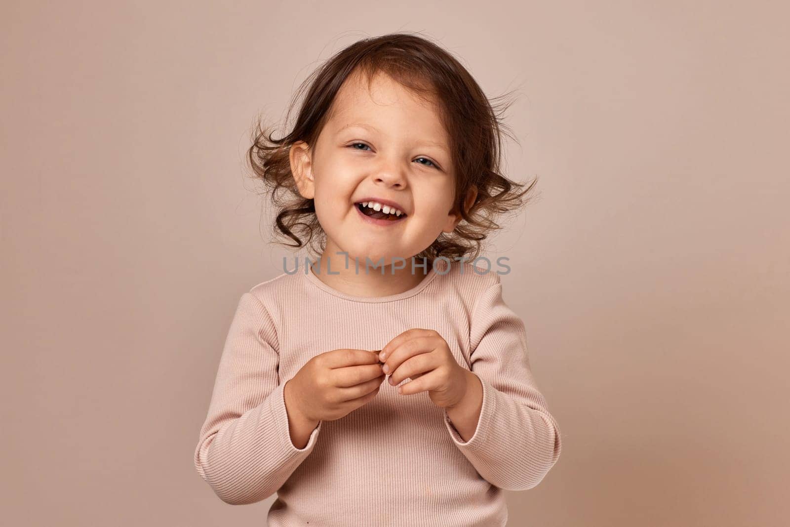 smiling child girl holding fruit pastille on beige background. healthy baby food.