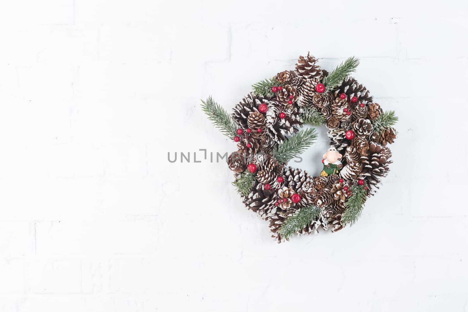 Elegant christmas wreath decorated pine cones and fir trees on white light grey wooden door. Christmas mood. Beautiful vintage door. Christmas mood: festive christmasy themed winter natural wreath on