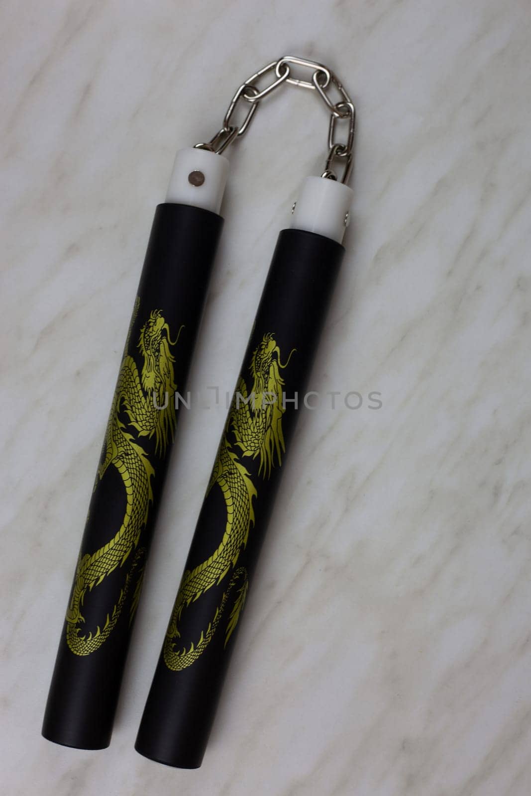 Eastern melee weapons, training nunchucks for learning strikes and improving body dexterity at home, unusual edged weapons on a white table, vertical photo