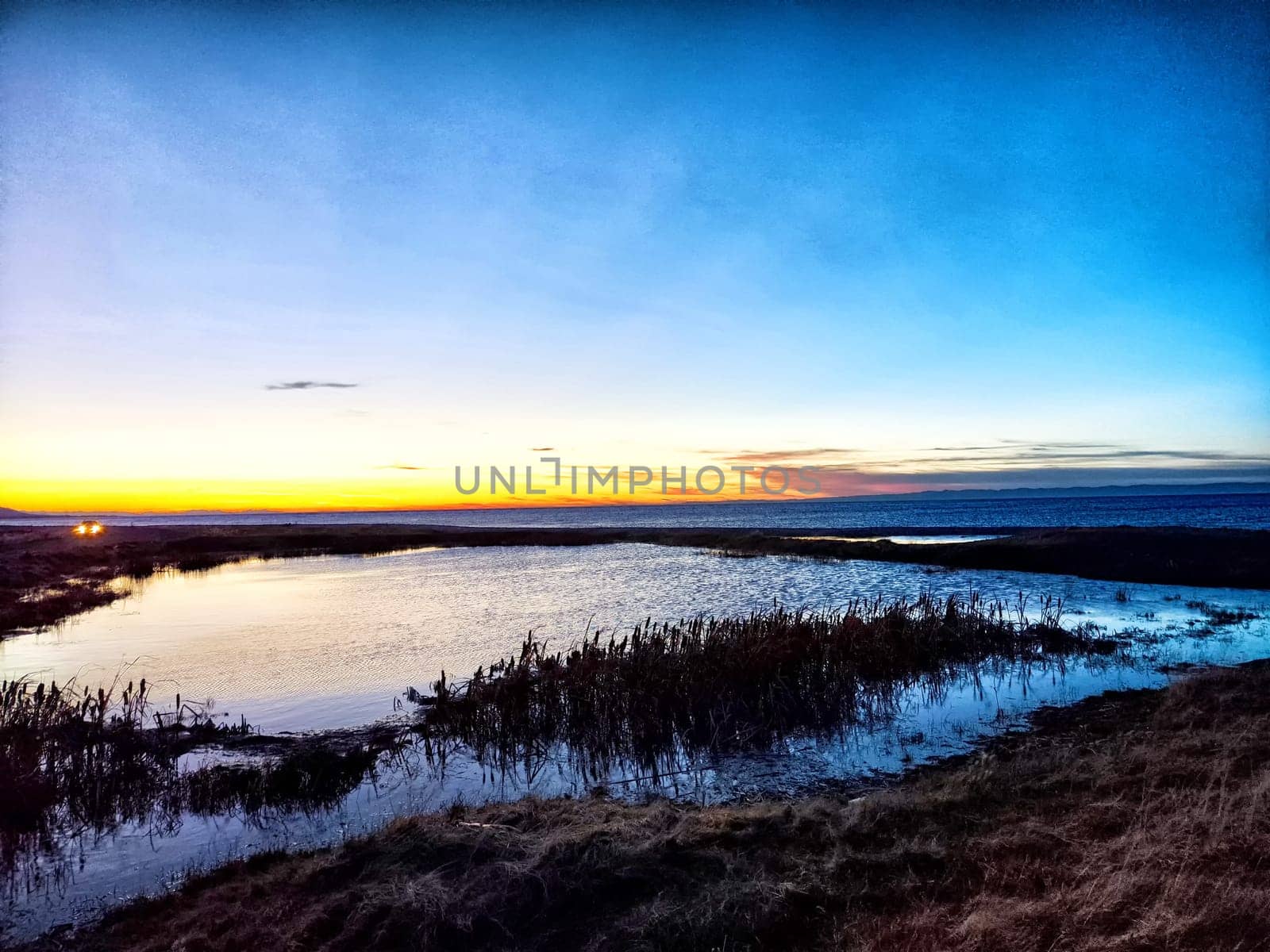 A stunning sunset paints the sky in vibrant colors while water reflects the serene beauty of the evening landscape.