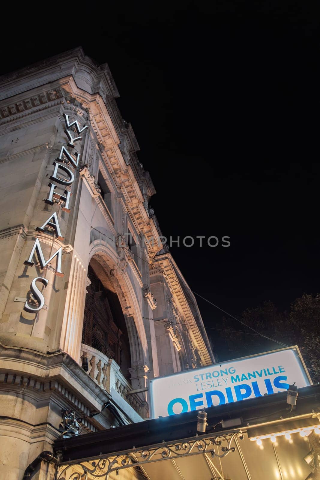 London, UK Nighttime view of Wyndhams theater entrance with large sign advertising "Oedipus", starring Mark Strong.