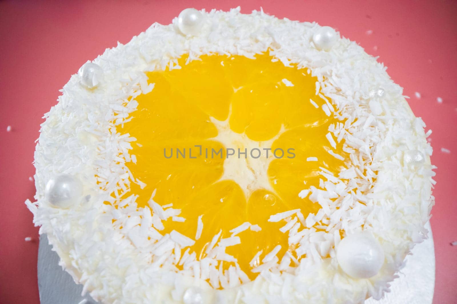 Delicious round cake with coconut shavings and orange jelly decorating the top, creating a joyful and appetizing dessert