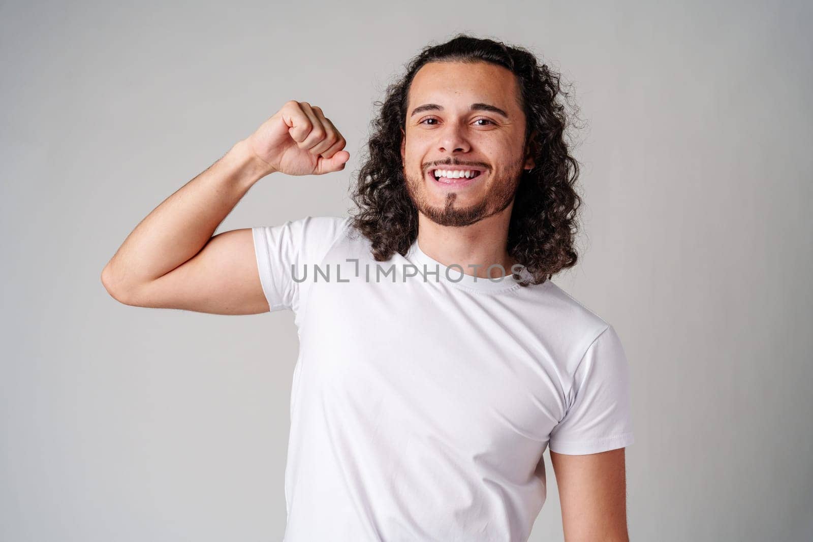 Happy man celebrating success with raised fists in a studio against a plain background close up