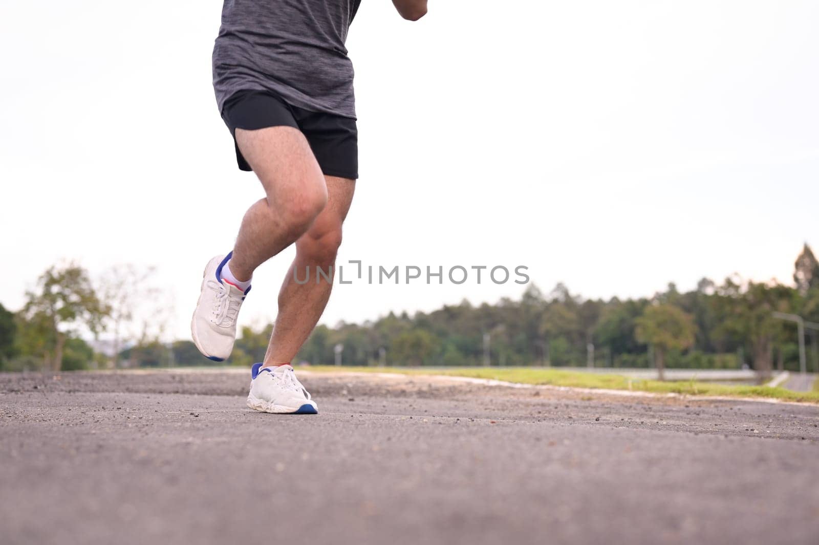 Male runner legs moving along a paved path in an outdoor. Fitness and active lifestyle.