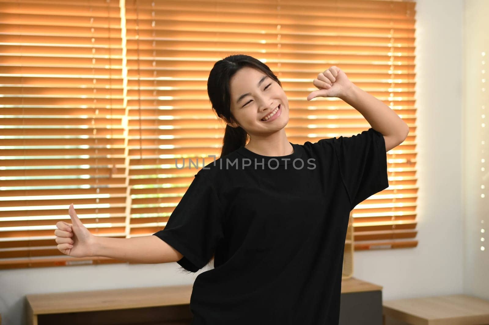 Teen asian girl enjoying freestyle dance practice in cozy living room. People and leisure activity concept.