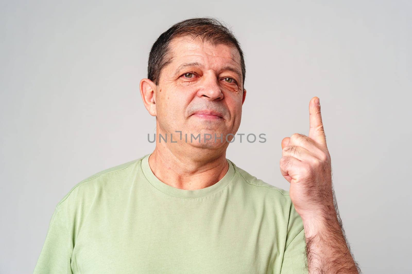 A man in a light green shirt raises his finger, signifying an important message close up