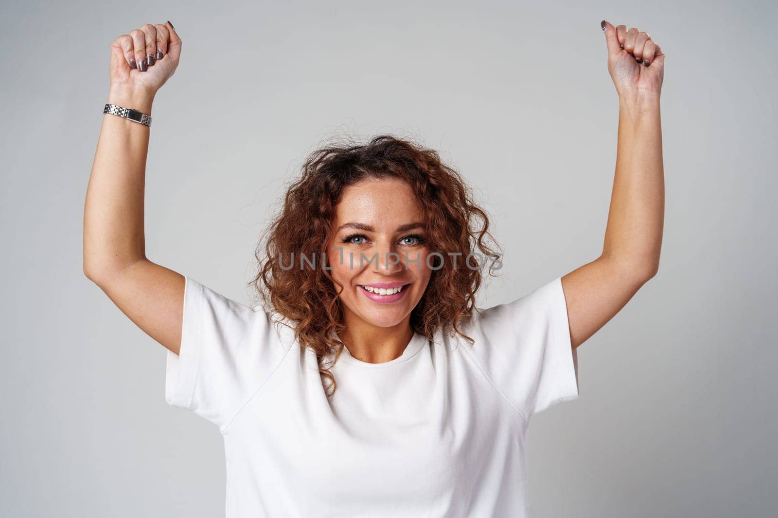 Young woman joyfully celebrates in casual attire against a neutral background close up