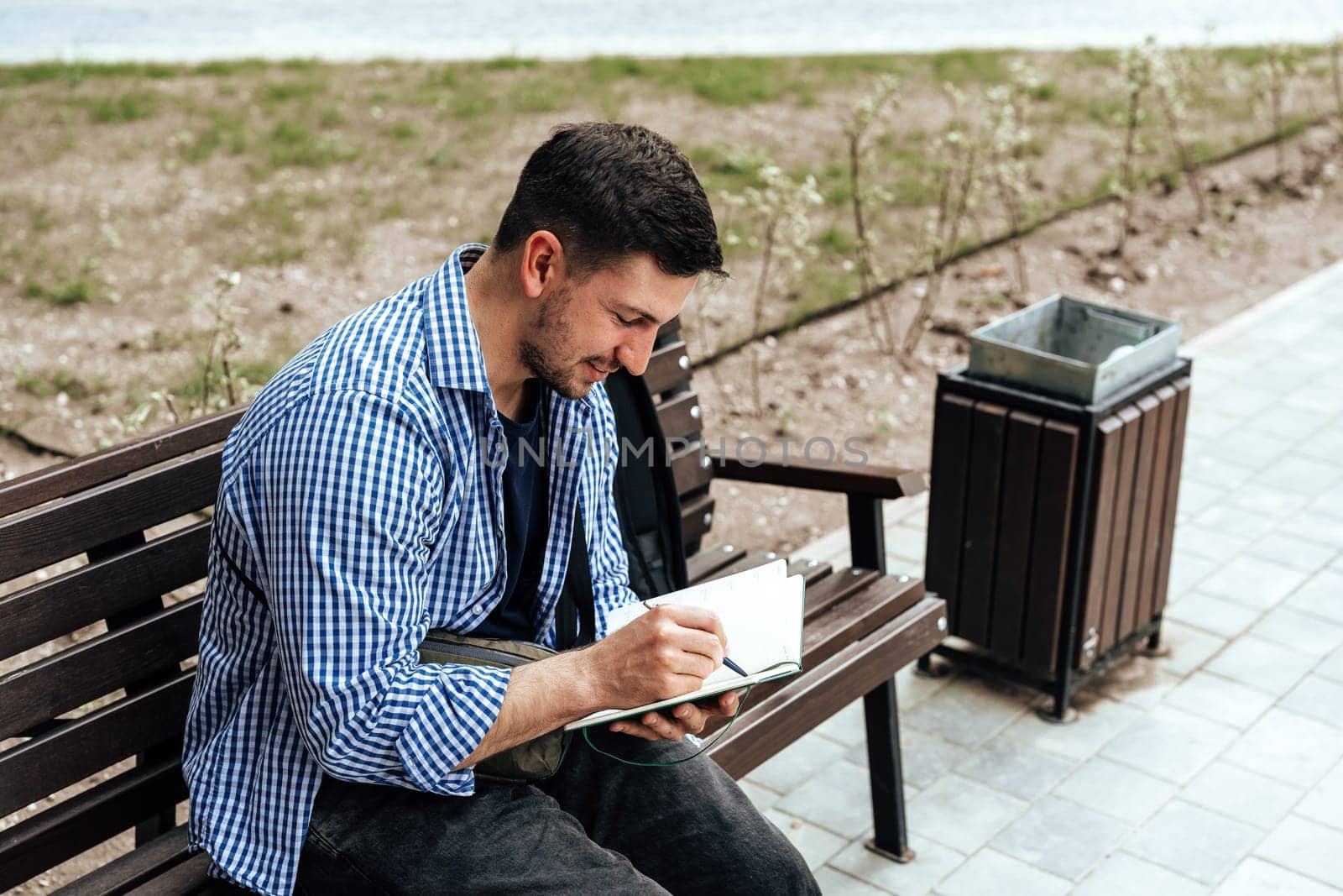 A person writes in a notebook while sitting on a park bench close up