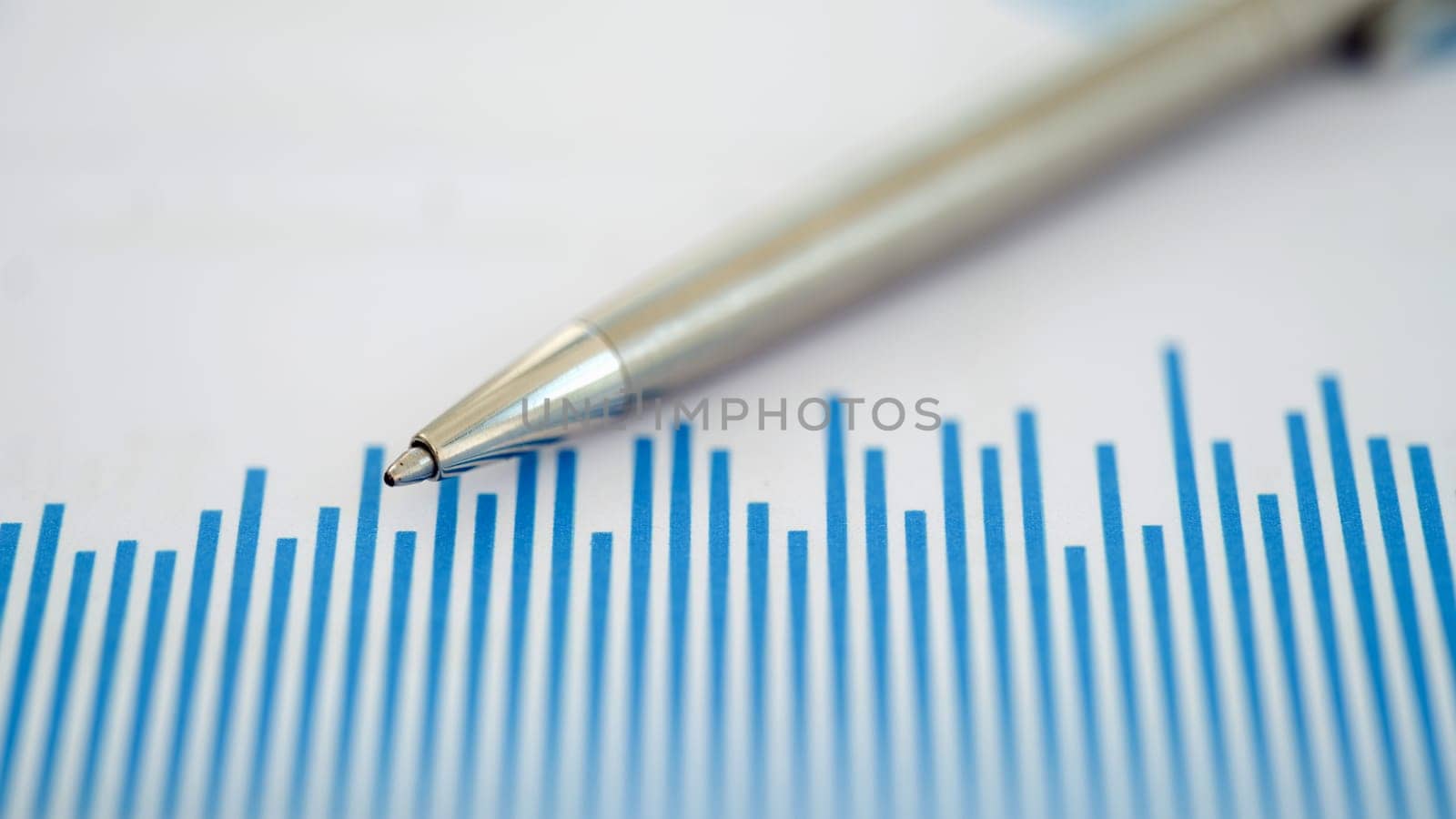 This striking image features a closeup of a pen on a blue chart with important financial data trends