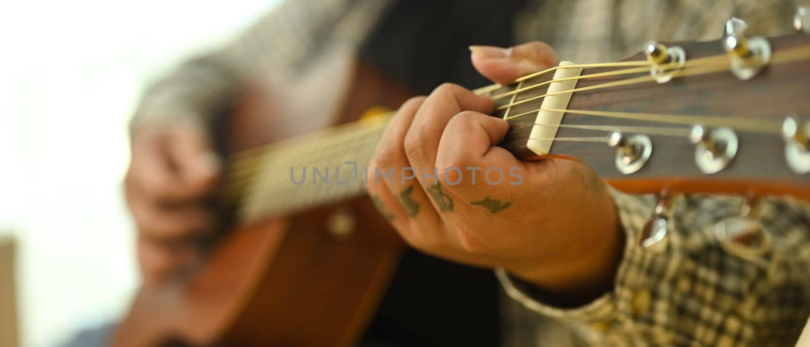 Close up of musician playing acoustic guitar at home.