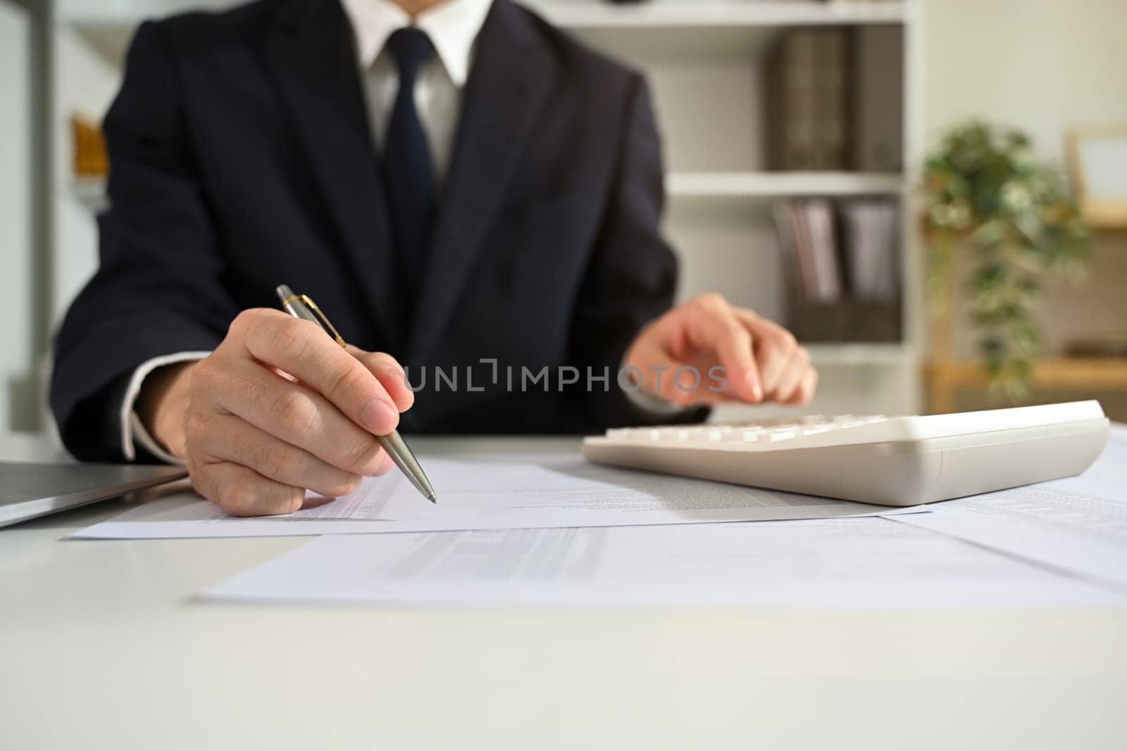 Focused accountant in black suit analyzing financial data at office desk.