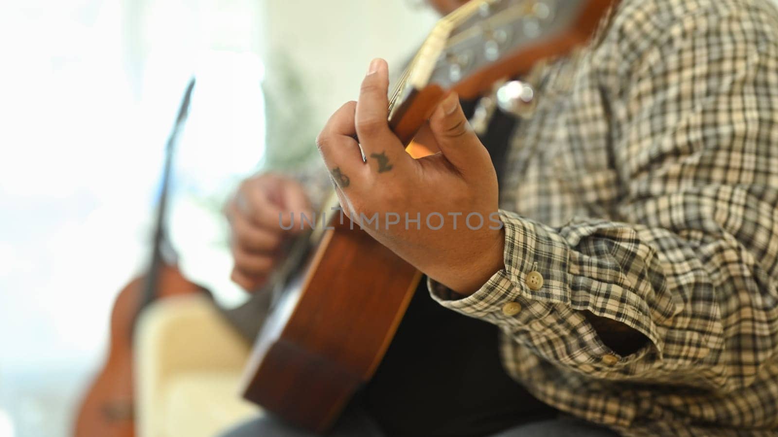 Close up of young man practicing guitar chords in living room.