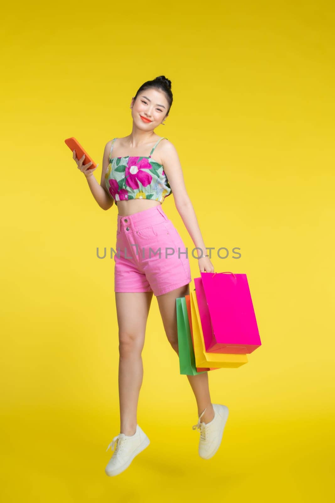 Young Asian woman with shopping bags reading text message on her phone by makidotvn