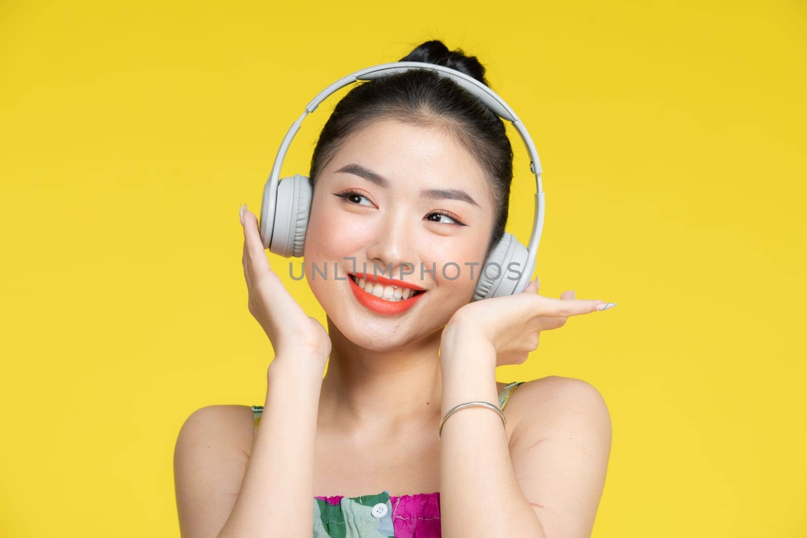 Young pretty Asian woman wearing headphones listening to music and dancing