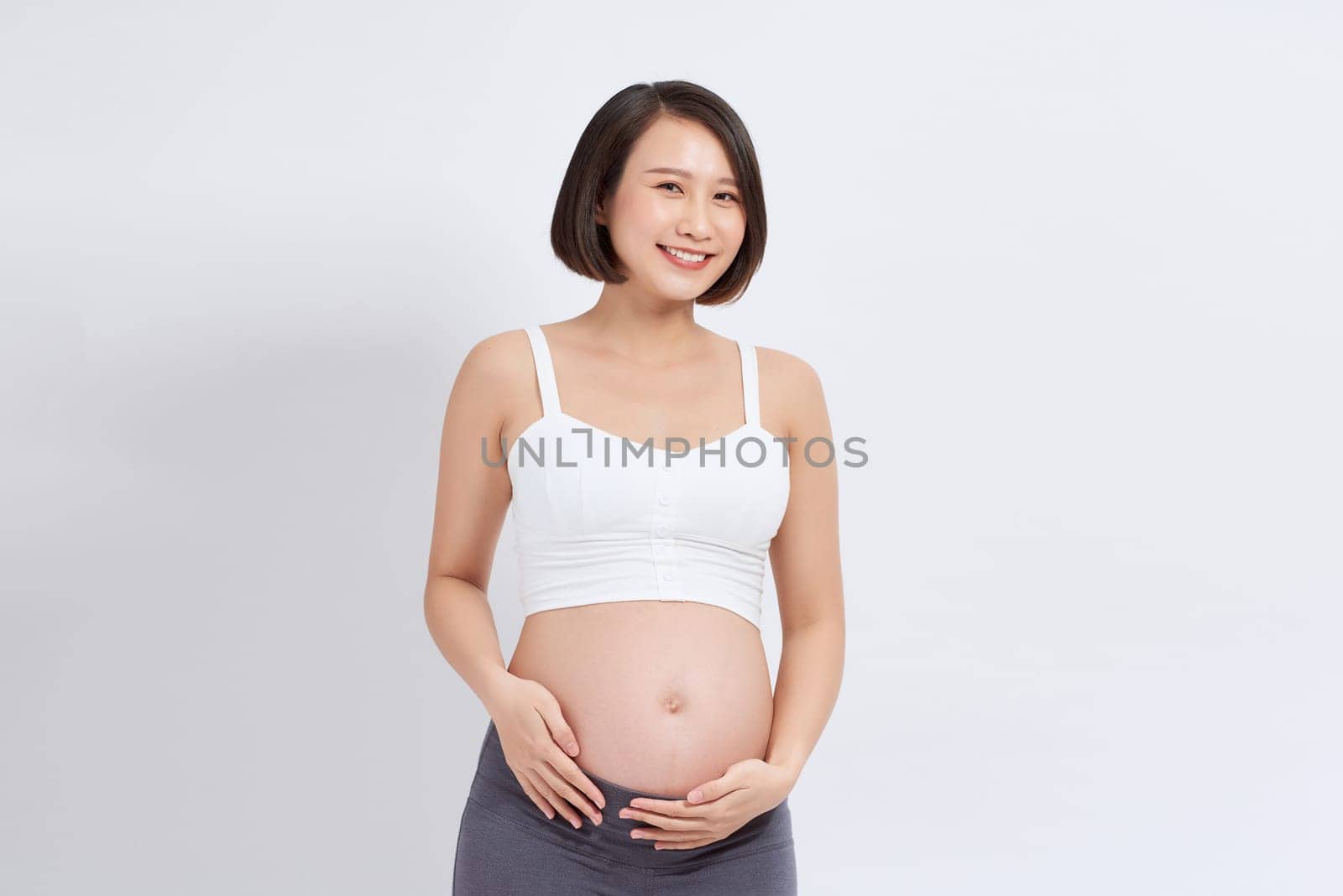 Pregnant woman touching belly on white