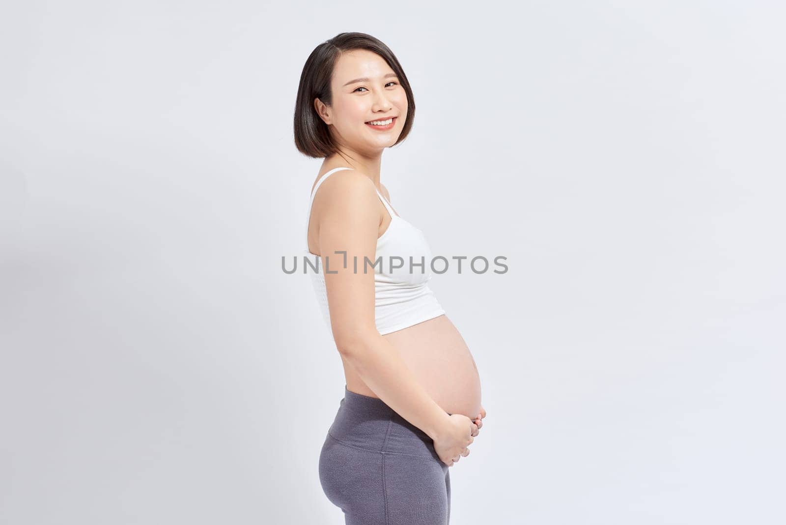 pregnant woman caressing her belly over white background