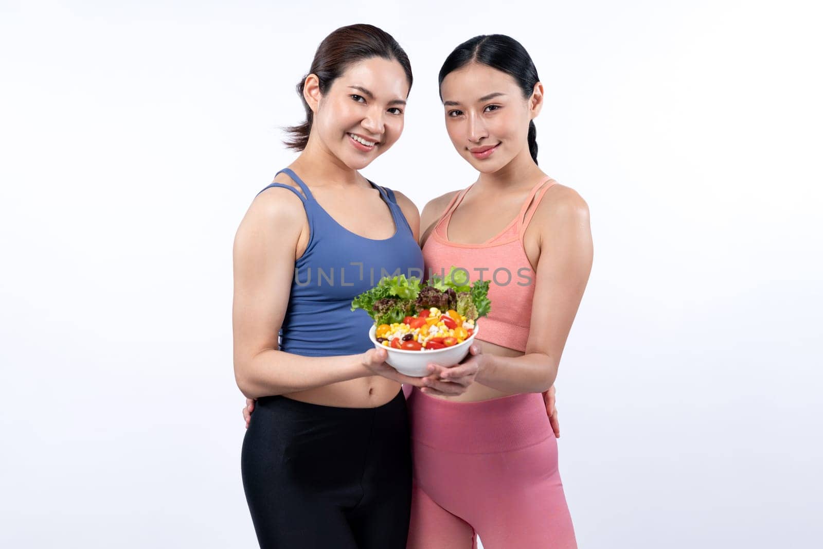 Asian woman in sportswear holding salad bowl on isolated background. Vigorous by biancoblue