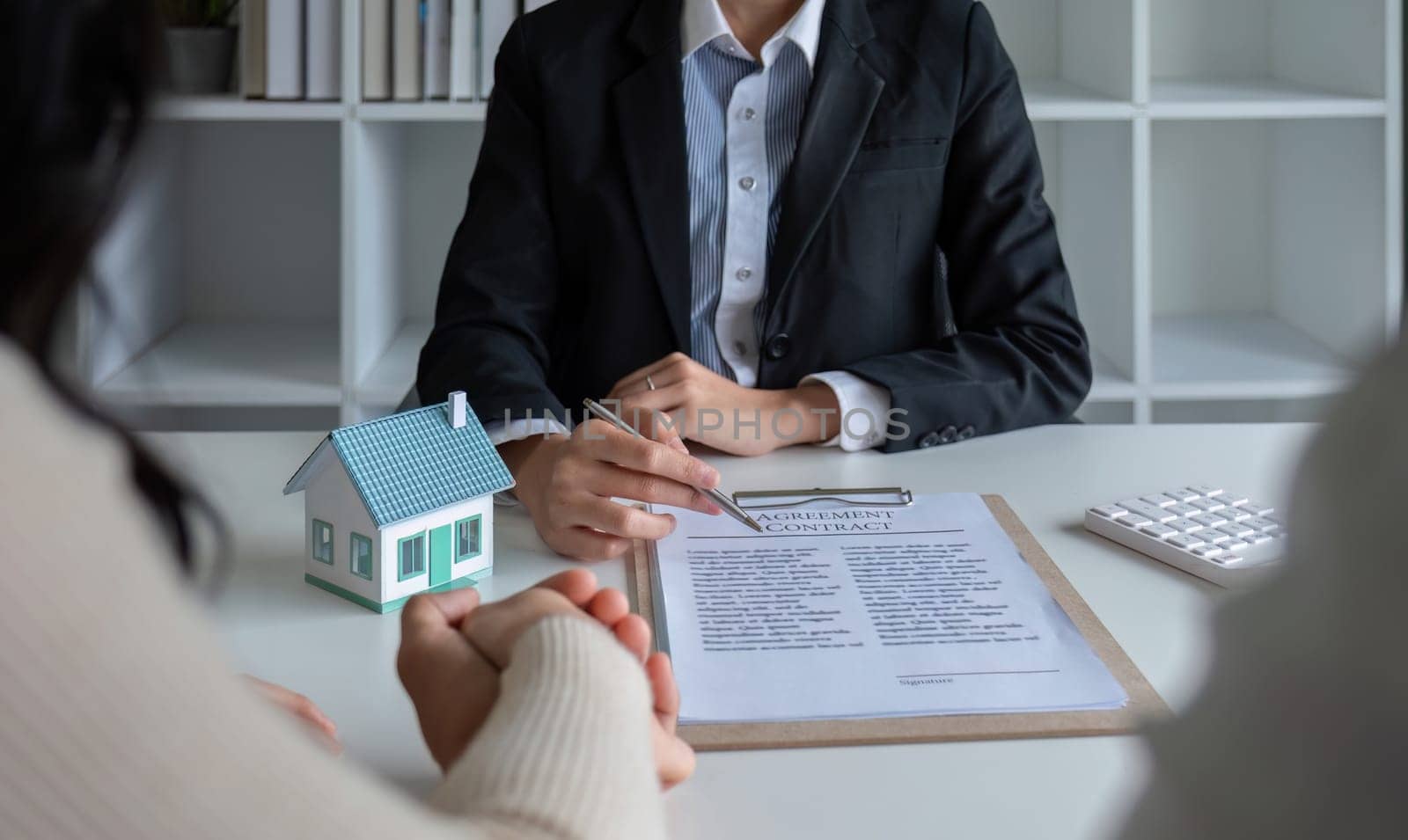 The real estate agent makes an offer to get the couple to sign a contract to buy the house. Happy male and female married customers make intimate deals with agents. real estate concept by wichayada