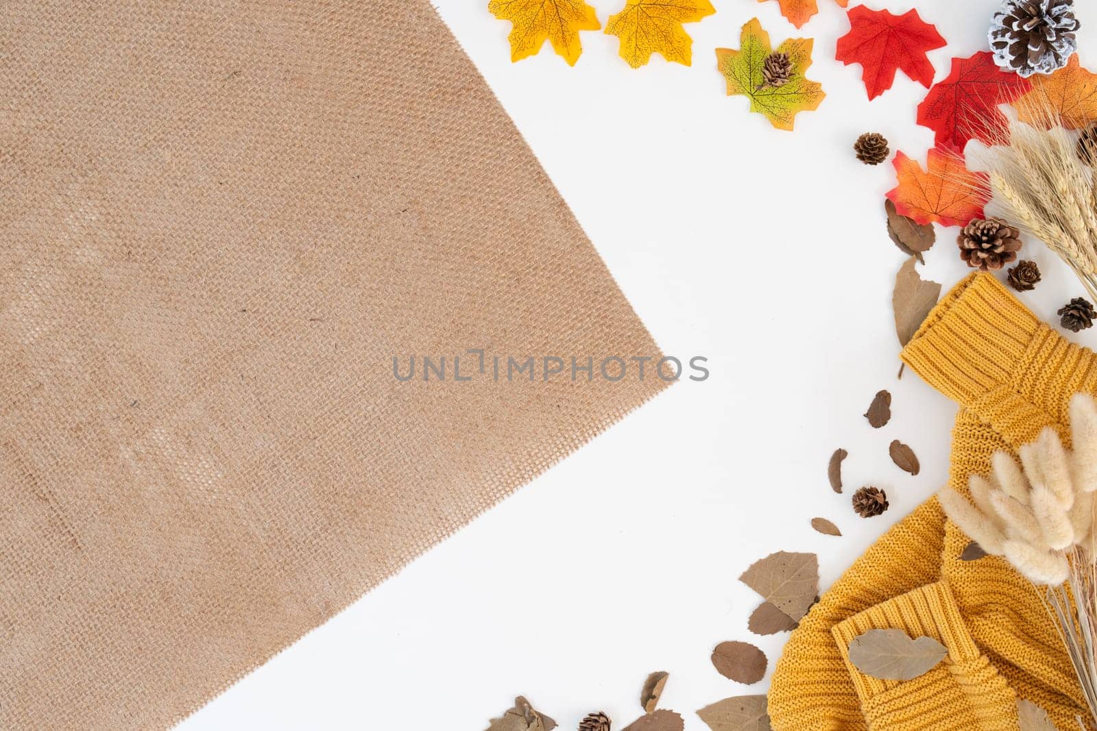 Top view above of modern office desk with yellow-red autumn leaves on white background with copy space. Place for your text. Work table with office supplies. concept cosy, cozy, seasonal autumn by nateemee