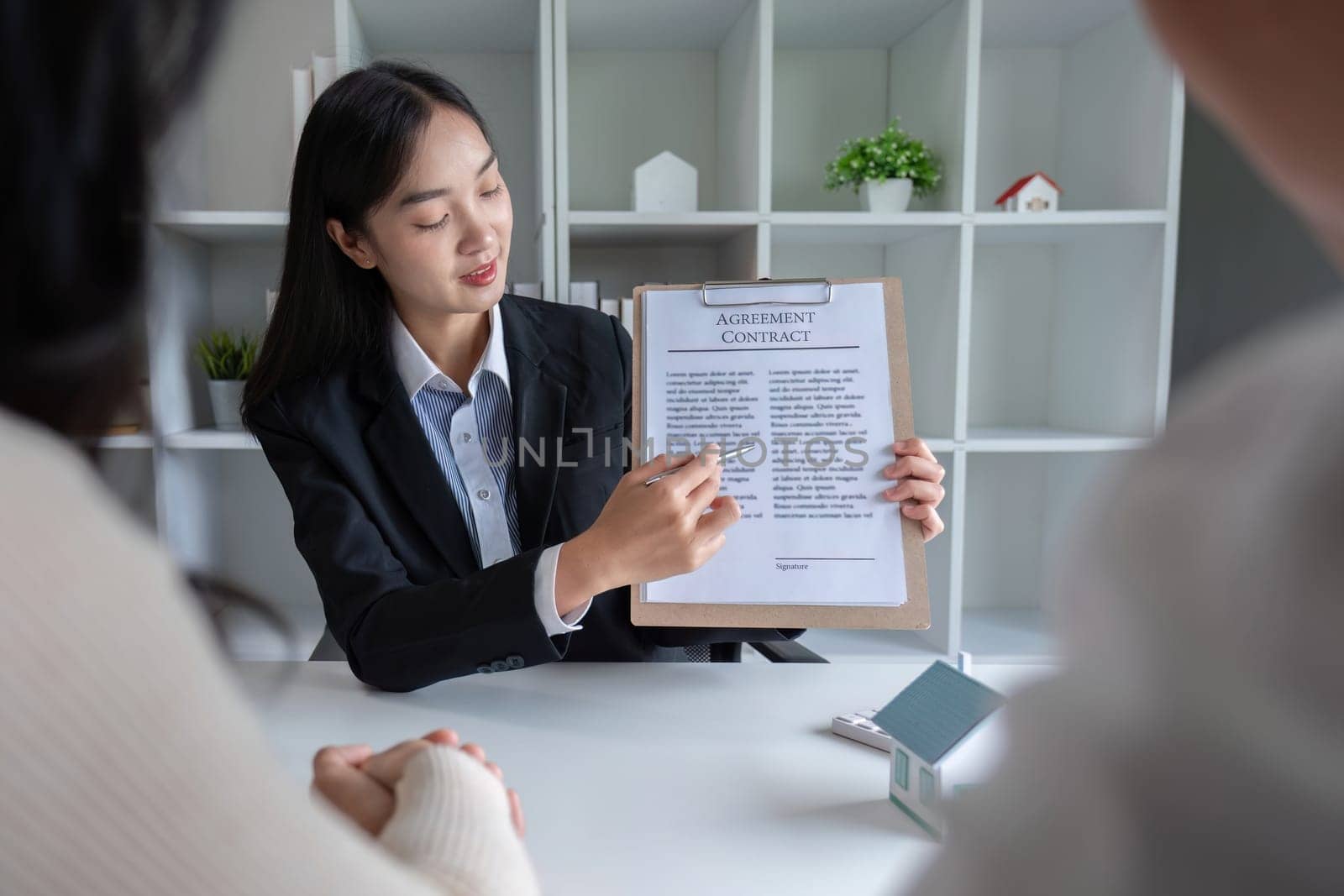 The real estate agent makes an offer to get the couple to sign a contract to buy the house. Happy male and female married customers make intimate deals with agents. real estate concept.