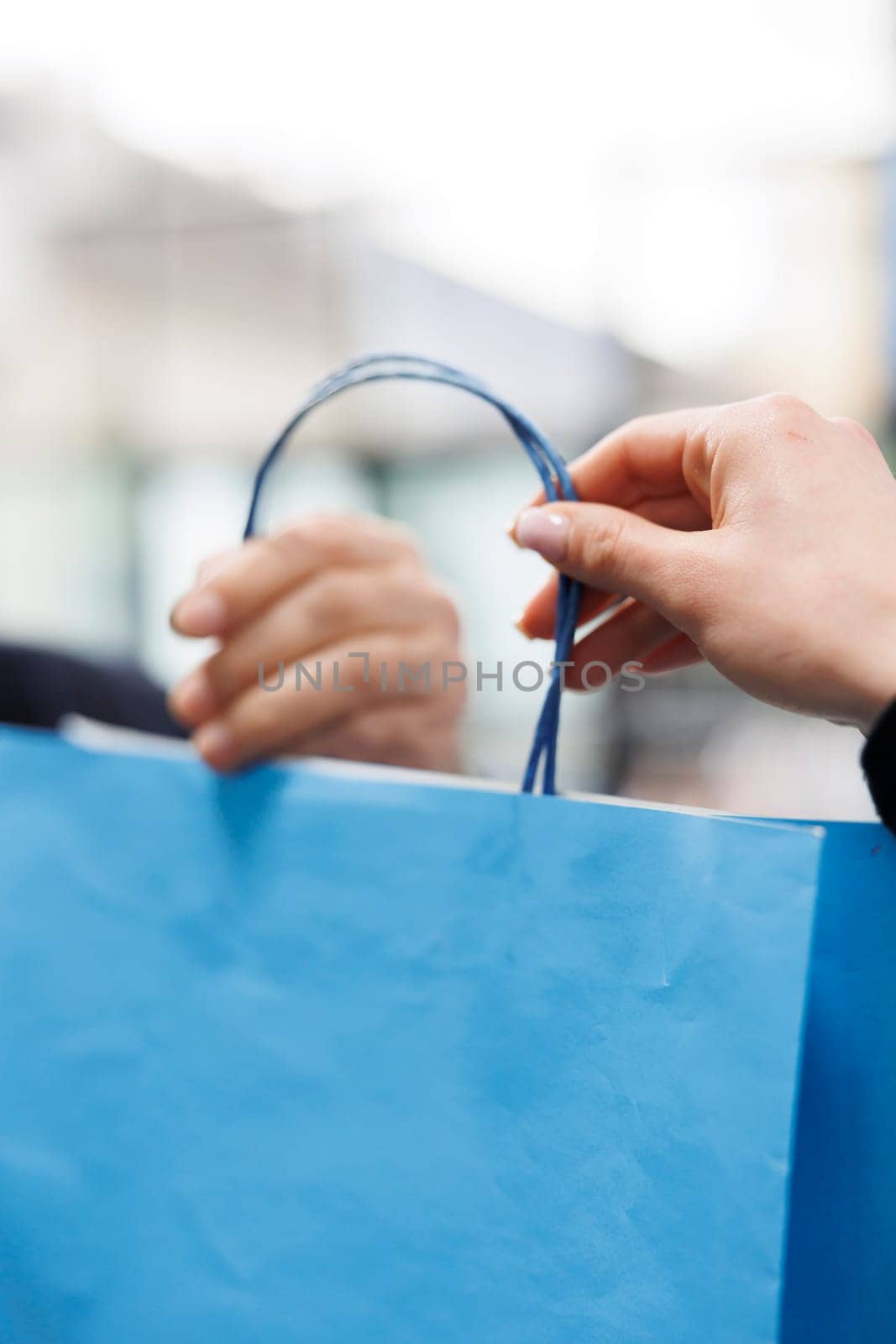 Senior customer receiving shopping bag with purchase from store manager, buying stylish casual wear in boutique shop. Elderly client making payment at cash register in clothing store. Close up