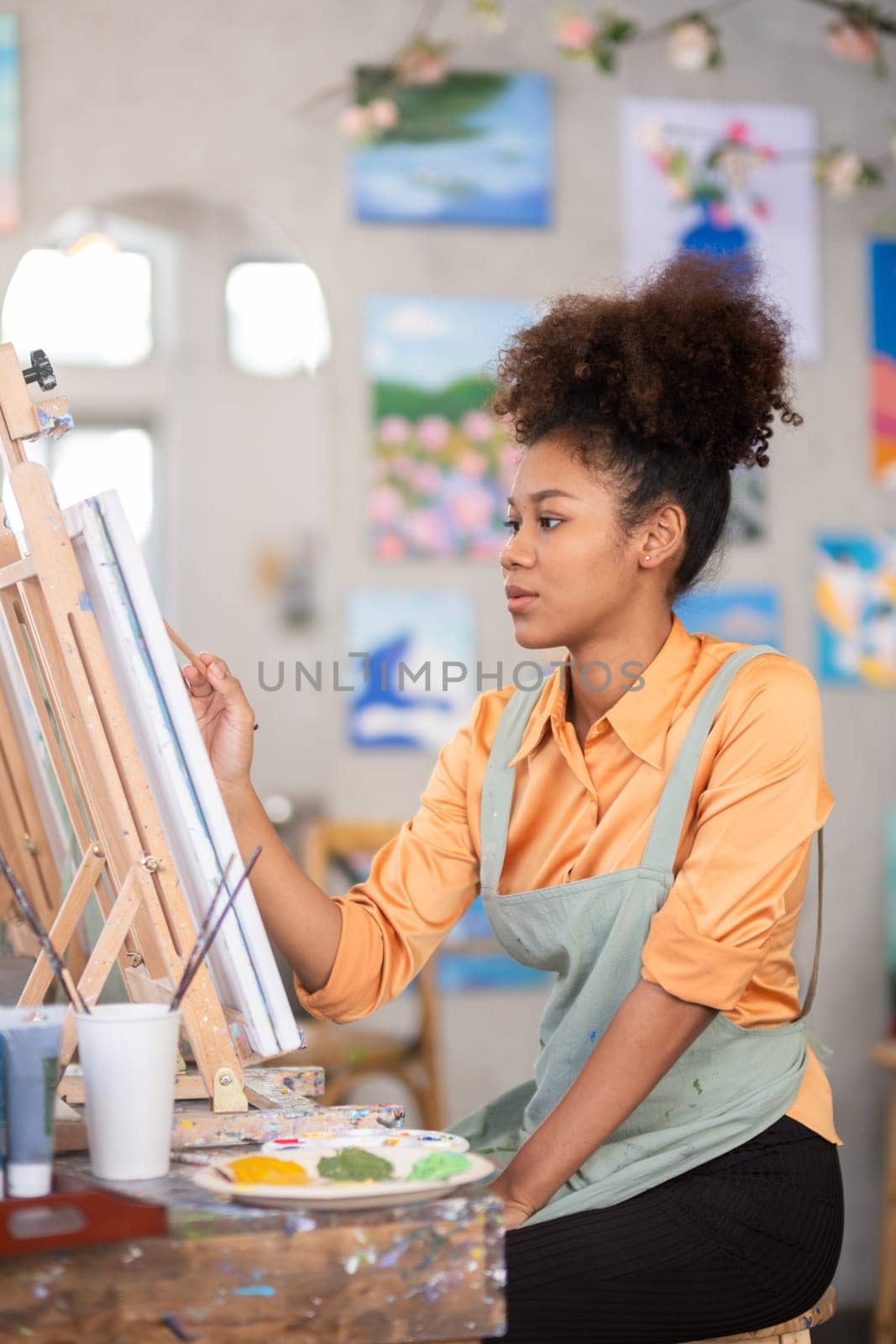 Portrait of a female African artist working on several art projects in her studio with great enjoyment..
