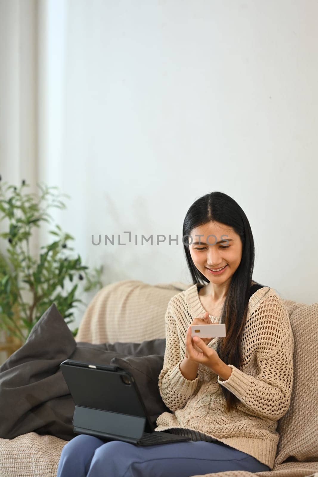 Happy female shopper using credit card for online shopping at home.