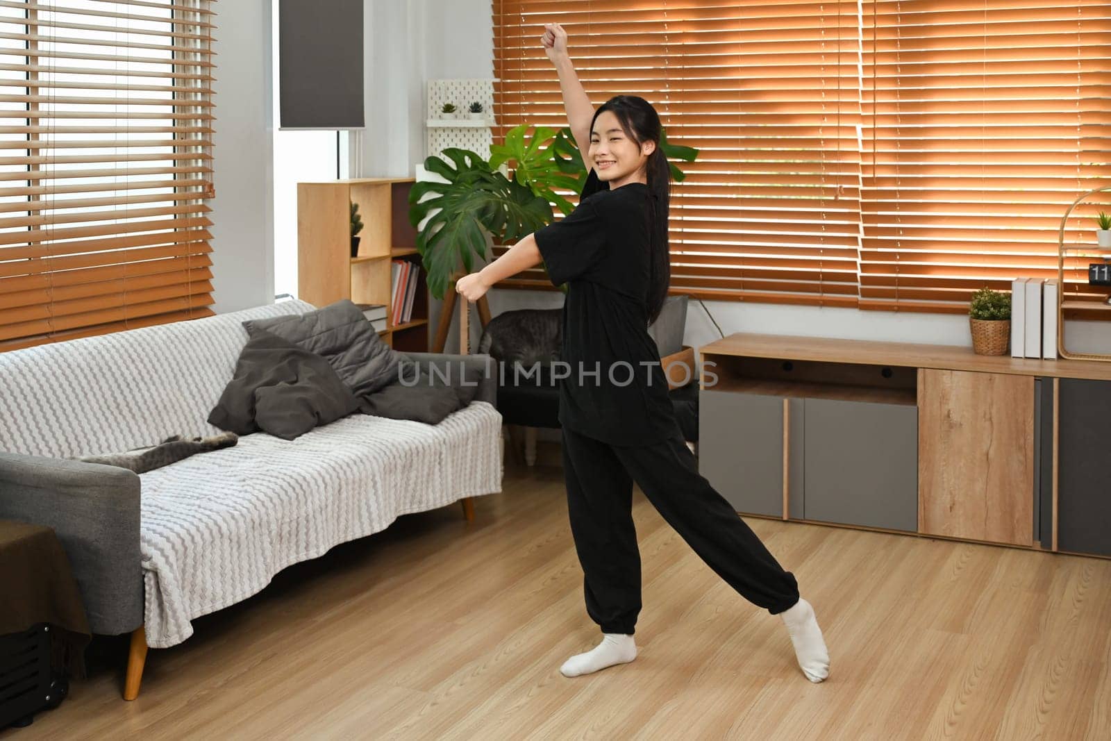 Joyful teenage girl practicing dance moves in her living room.