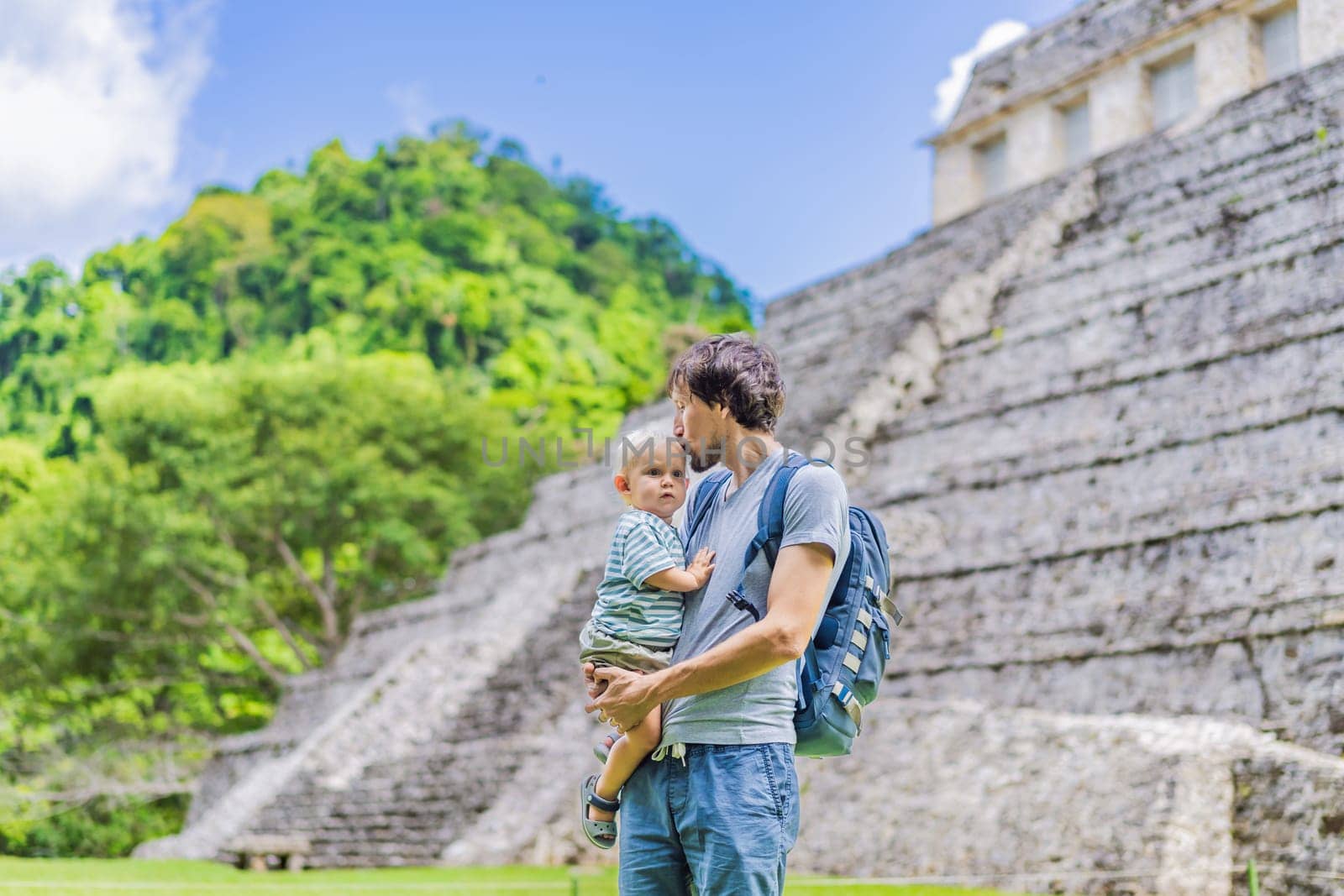 Mother with his toddler son exploring the ancient pyramids of Palenque, Mexico, surrounded by dense jungle. Cultural heritage and adventure travel concept.