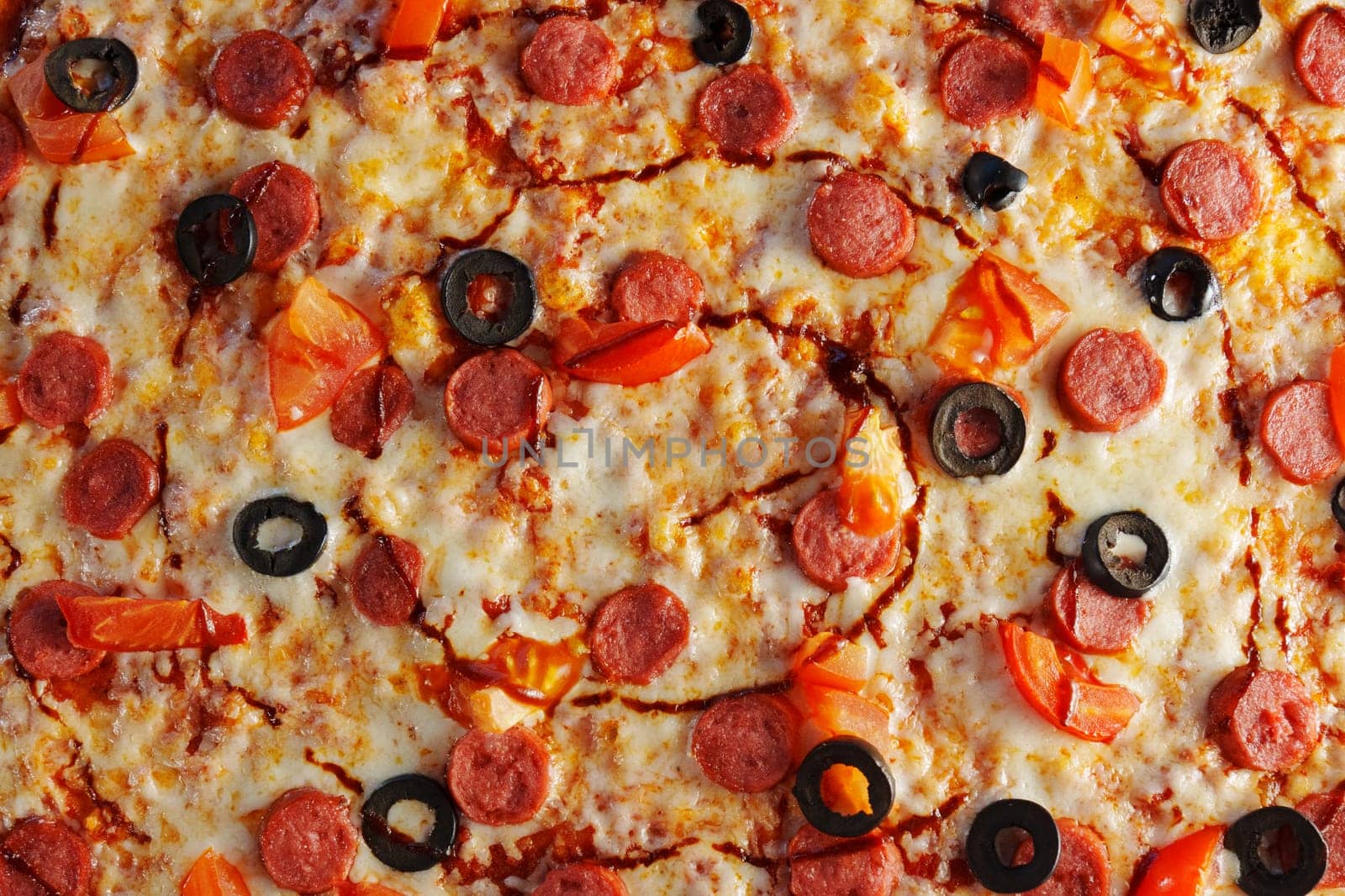 Delight in a mouthwatering pizza adorned with pepperoni slices and black olives, fresh tomato pieces, and a rich swirl of sauce, perfect for any occasion.