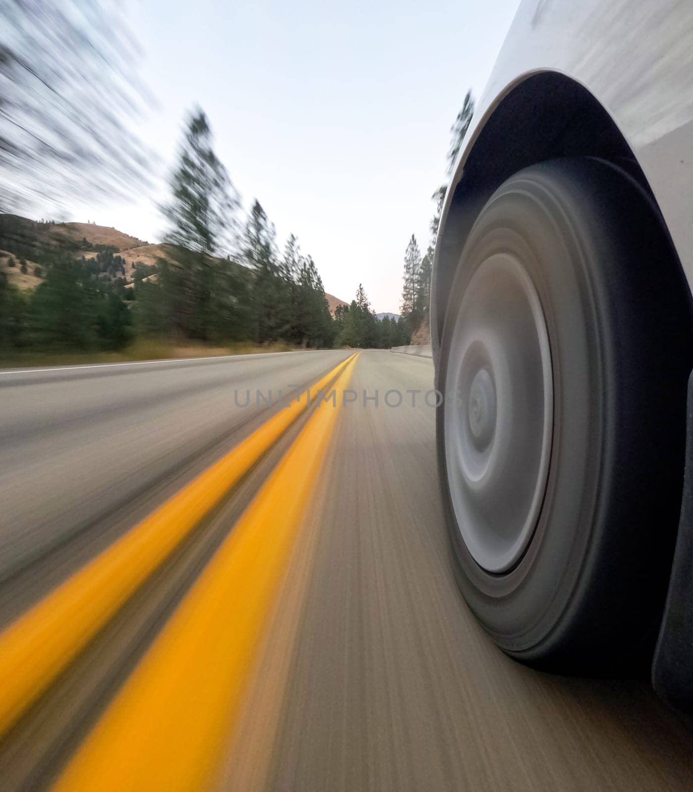 A dynamic view of a car wheel speeding on an open road through a scenic forest. Capturing motion, adventure, and freedom in one exciting shot.