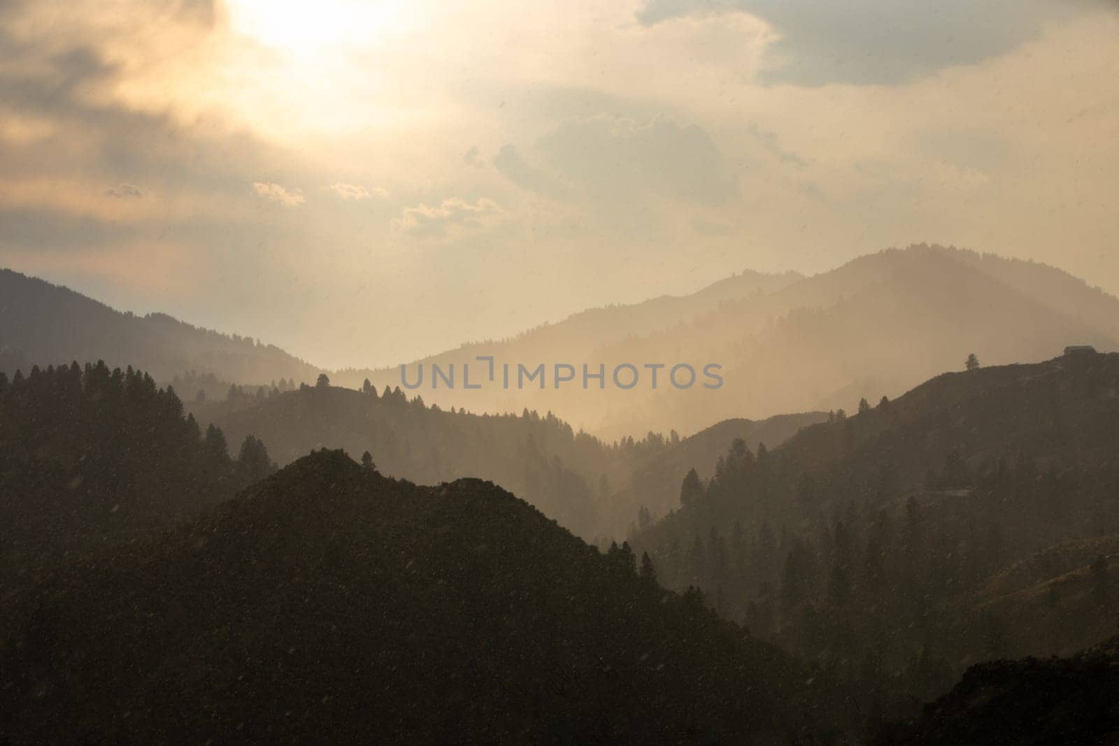 Serene landscape of a mountain range bathed in warm sunset light, shrouded in mist for a tranquil and mysterious atmosphere. Ideal for nature, tranquility, and outdoor themed projects.
