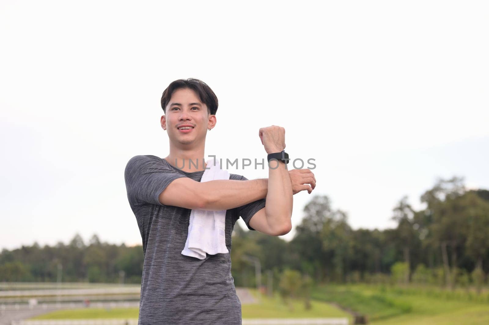 Relaxed asian man stretching muscles after jogging in the park.