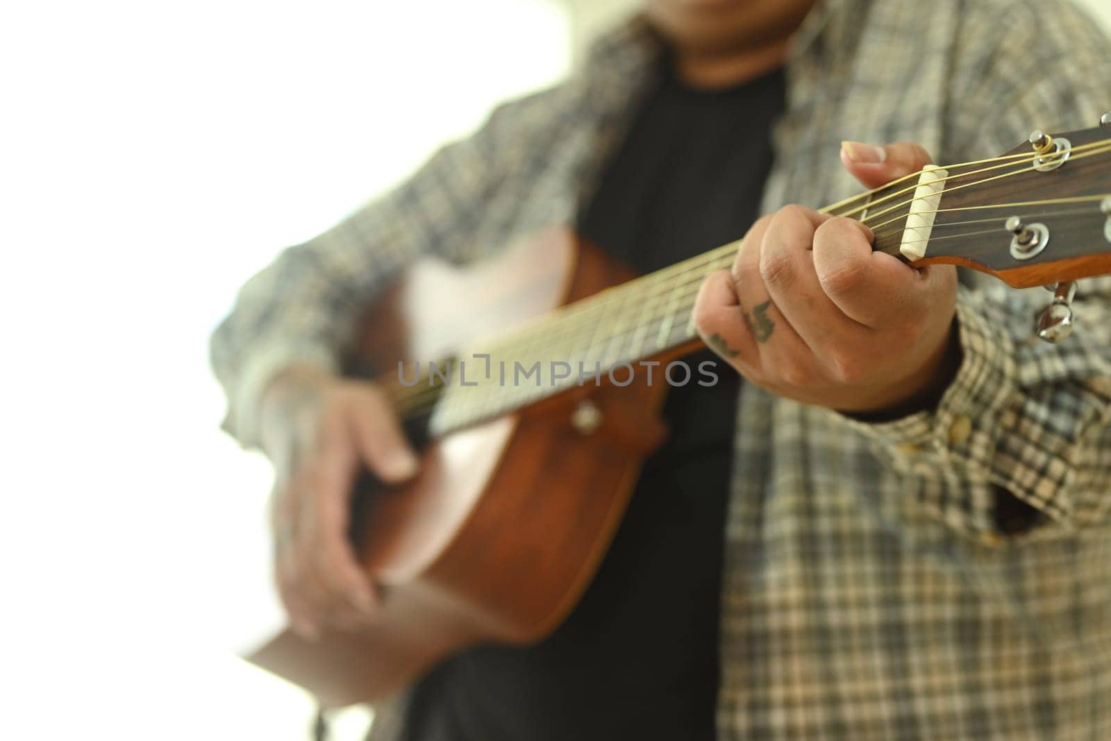 Close up of man practicing acoustic guitar chords. Leisure activity and hobby concept.