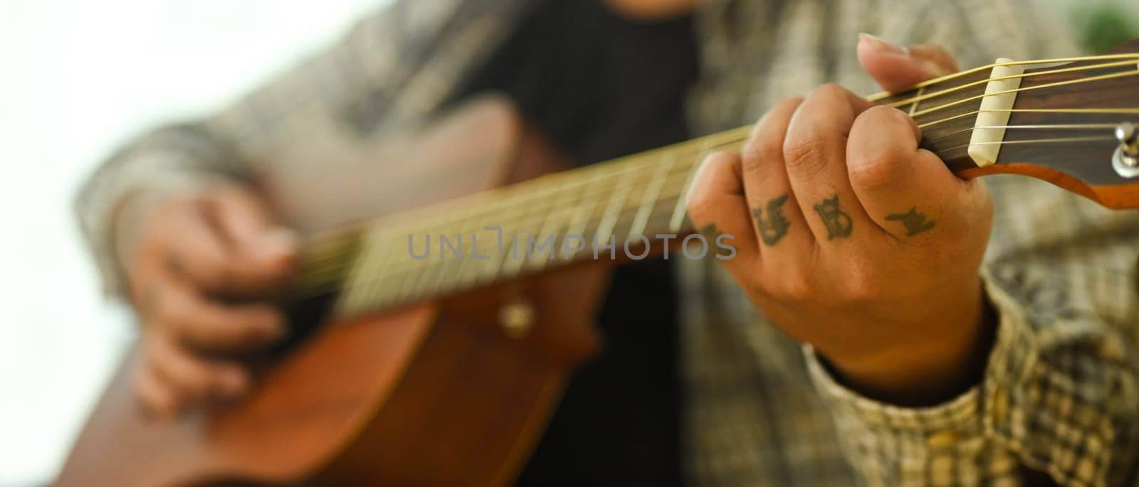 Close up of man practicing acoustic guitar chords. Leisure activity and hobby concept.