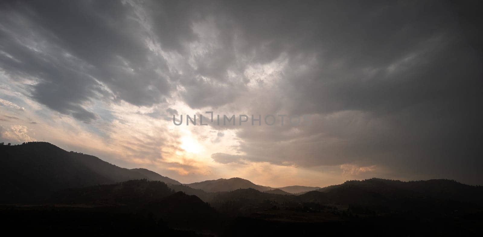 A captivating sunrise over a mountainous landscape with dramatic clouds. The scene evokes serenity and awe, highlighting the beauty of nature's interaction with light and shadow.