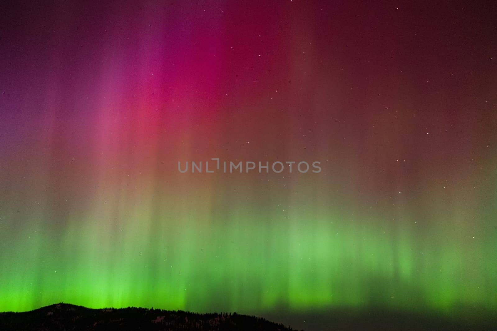 Spectacular aurora borealis illuminating the night sky with vibrant colors. This natural wonder showcases the beauty of the universe with stunning hues of green and red.