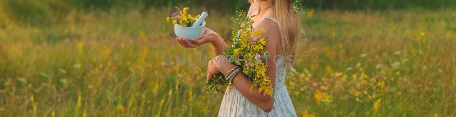 Woman in a meadow with medicinal herbs. Selective focus. Nature.